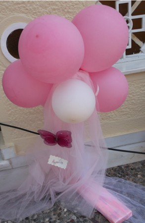 Ροζ λουλουδάκι από μπαλόνια σε στολισμένη βάση στην είσοδο της εκκλησίας